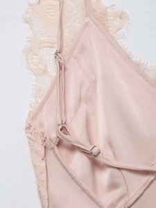 Détail d'un caraco en satin rose montrant la dentelle et le curseur de sangle réglable