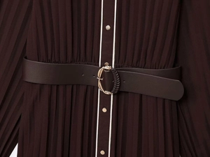 Détail de la robe plissée marron foncé montrant la ceinture avec boucle dorée ronde