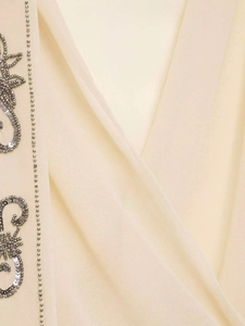 Détail de l'encolure en V avec broderie de paillettes argentées sur mousseline beige
