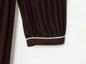 Détail des manches plissées d'une robe midi marron foncé avec passepoil blanc contrasté