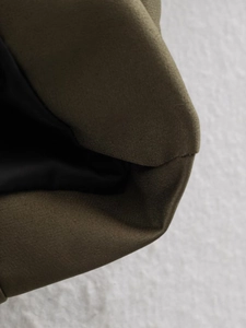Dettaglio del bomber in twill verde oliva con cuciture pulite e fodera nera lucida