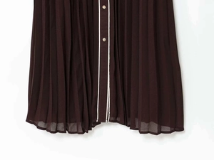 Détail de la robe midi plissée café avec liseré blanc et bouton métallique doré décoratif