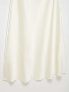 Détail d'une robe longue en satin blanc crème montrant la texture de soie et l'ourlet fluide