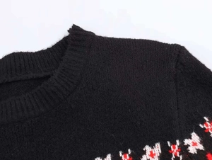 Detail van de gebreide wintertrui met rood en wit jacquardpatroon op zwarte gebreide stof