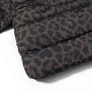 Detailed macro view of quilted dark leopard print fabric on a padded winter puffer jacket