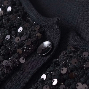 Giacca da donna in maglia nera con paillettes e bottone tondo, focus su trama e dettagli