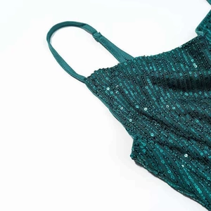 Detailed close-up of dark green sequin dress showing fine spaghetti straps and texture