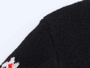 Détail de la couture de l'épaule et du motif festif de Noël sur un pull en tricot noir
