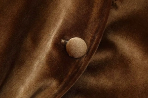 Primer plano de tela de terciopelo marrón con botón forrado a juego y detalles de costura