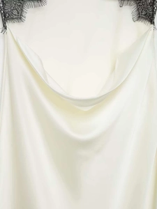 Vue macro détaillée de la bordure en dentelle noire sur robe longue en satin crème
