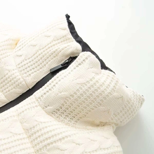 Close-up of knit jacket with black zipper detail and textured cream cable stitch