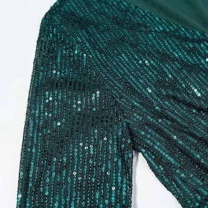 Detail of emerald green sequins arranged in vertical stripes on long sleeve dress