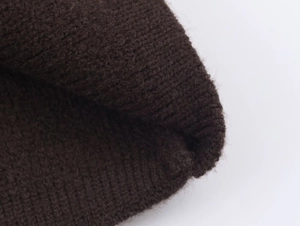 Macro shot of dark brown knitted fabric texture showing premium wool blend details