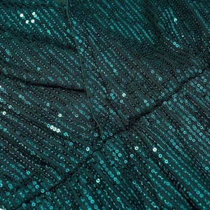 Macro detail of dark green sequins on elegant long sleeve dress with metallic shine