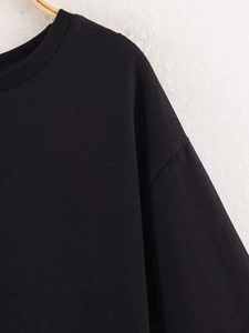 Détail de la texture du tissu en maille noire et du col rond classique d'un t-shirt ample