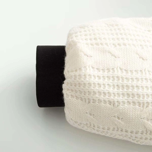 Close-up of thick cable knit texture on winter jacket sleeve in off-white and black
