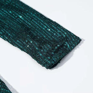 Close-up of emerald green sequins on the dress showing shimmering metallic texture
