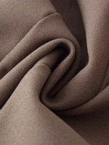 Macro shot of dark camel wool fabric texture and soft drapes on a stylish autumn coat