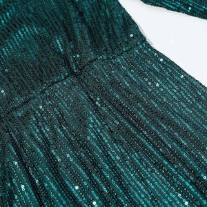 Detailed view of emerald green sequin embroidery with vertical stripe pattern on dark mesh