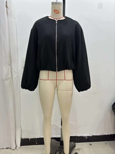 Detailed close-up of a black zip-up bomber jacket with elastic cuffs on a mannequin