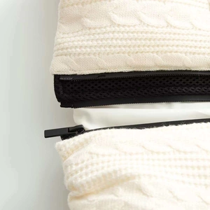 Detailed close-up of white cable knit fabric with a black zipper and mesh lining details