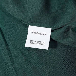 Close-up detail of dark green sequin dress wash label showing 100% polyester material