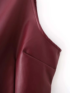 Detailed close-up of wine red faux leather texture and double stitching on the dress