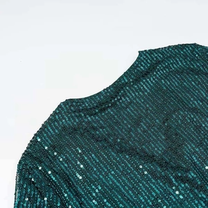 Close-up of deep emerald green sequins stitched on mesh for an elegant dress detail