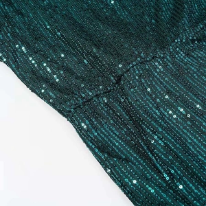 Detailed macro shot of dark green sequins arranged in vertical stripes on evening fabric
