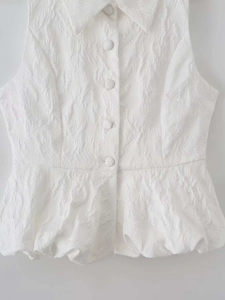Détail du haut blanc sans manches avec basque et tissu jacquard texturé à motif plumes