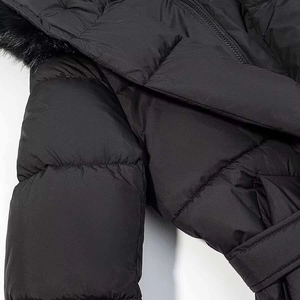 Détail du manteau matelassé noir avec col en fausse fourrure et ceinture à la taille