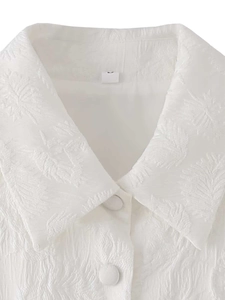 Détail du haut blanc sans manches montrant le tissu jacquard et les boutons recouverts