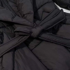 Détail de la veste d'hiver montrant la ceinture nouée et les coutures matelassées