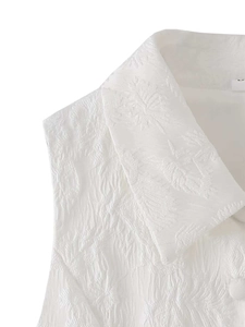 Détail du haut sans manches blanc montrant le tissu jacquard et les boutons assortis