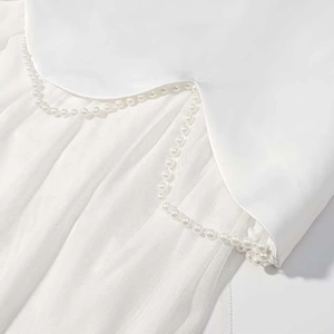 Détail de bord de robe en satin blanc avec maille cousue et garniture de perles fines