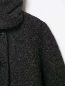 Close-up of charcoal grey fuzzy texture fabric and matte black buttons on a plush winter coat
