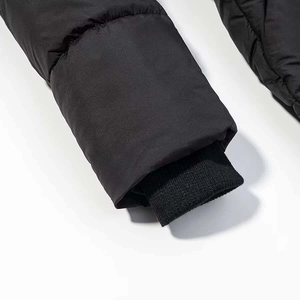 Détail d'un manteau d'hiver noir montrant les poignets coupe-vent et les coutures fines