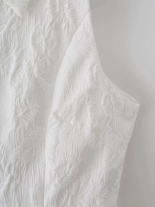 Gros plan du haut blanc sans manches montrant la texture jacquard 3D aux motifs de feuilles