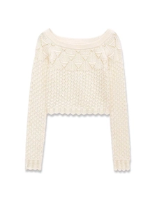 Detail of cream knit sweater showing hollow crochet patterns and scalloped edges
