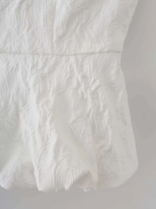 Vue détaillée d'un haut blanc sans manches en jacquard floral avec plis à la taille