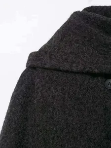 Close-up detail of dark grey plush mohair fabric texture and black button on short coat
