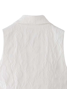 Détail macro du haut sans manches blanc montrant la texture du tissu jacquard floral 3D