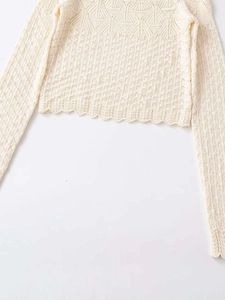Detail showing knit textures and scalloped hemline of the cream long sleeve top