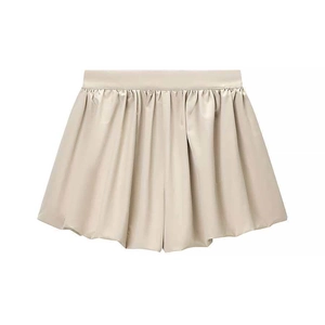 Detail of beige satin high-waisted pleated shorts with smooth silky texture and elastic waistband