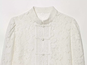Close-up of white lace blouse featuring mandarin collar and traditional knot buttons
