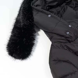 Détail d'une parka d'hiver avec col en fourrure noire et boutons-pression métalliques
