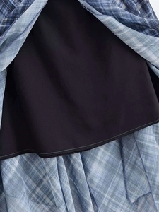 Détail d'une jupe midi à carreaux bleus montrant la texture et la doublure noire