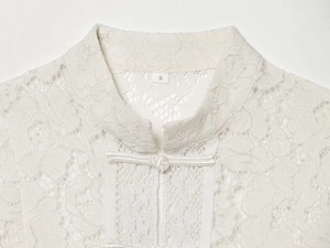 Close-up of elegant white lace shirt collar with traditional frog button and stand collar