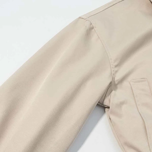 Close-up of fine stitching and pocket detail on a minimalist beige tailored jacket