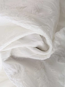 Gros plan du tissu jacquard blanc avec texture florale 3D détaillée et fini soyeux